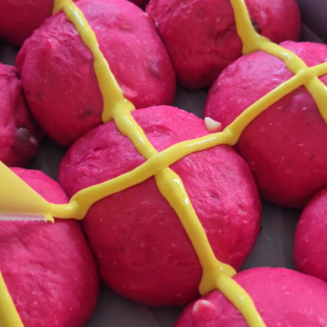 Bright pink hot cross buns marked with yellow crosses