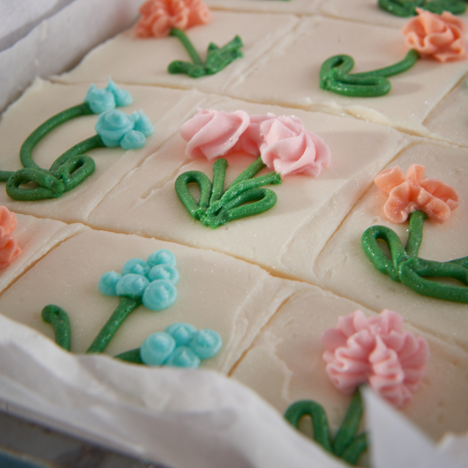 School cake squares decorated with pink, peach and blue piped flowers