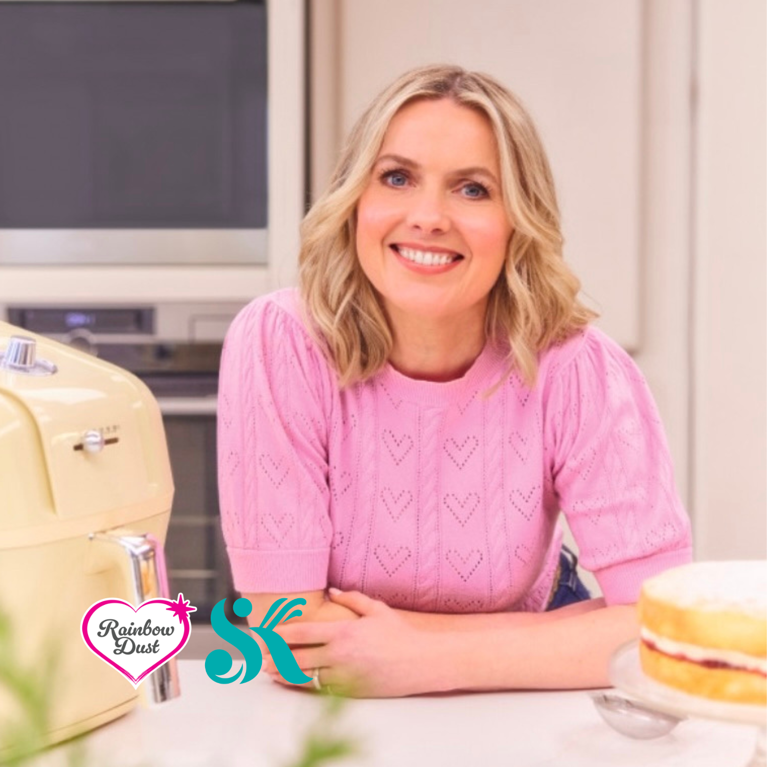Juliet Sear seated beside a cake in the Rainbow Dust kitchen