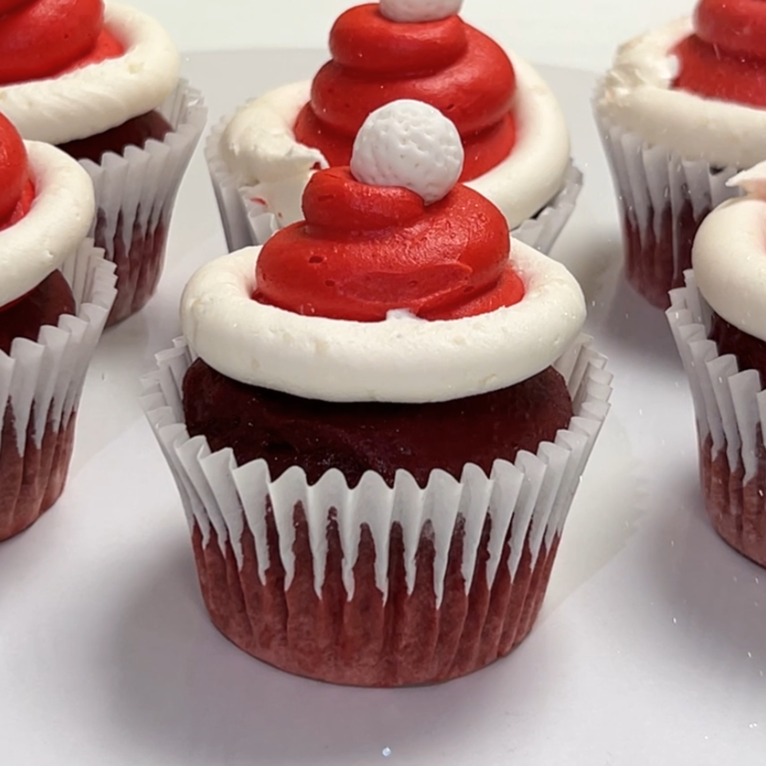 Cupcakes topped with red Santa hat buttercream and white marshmallows