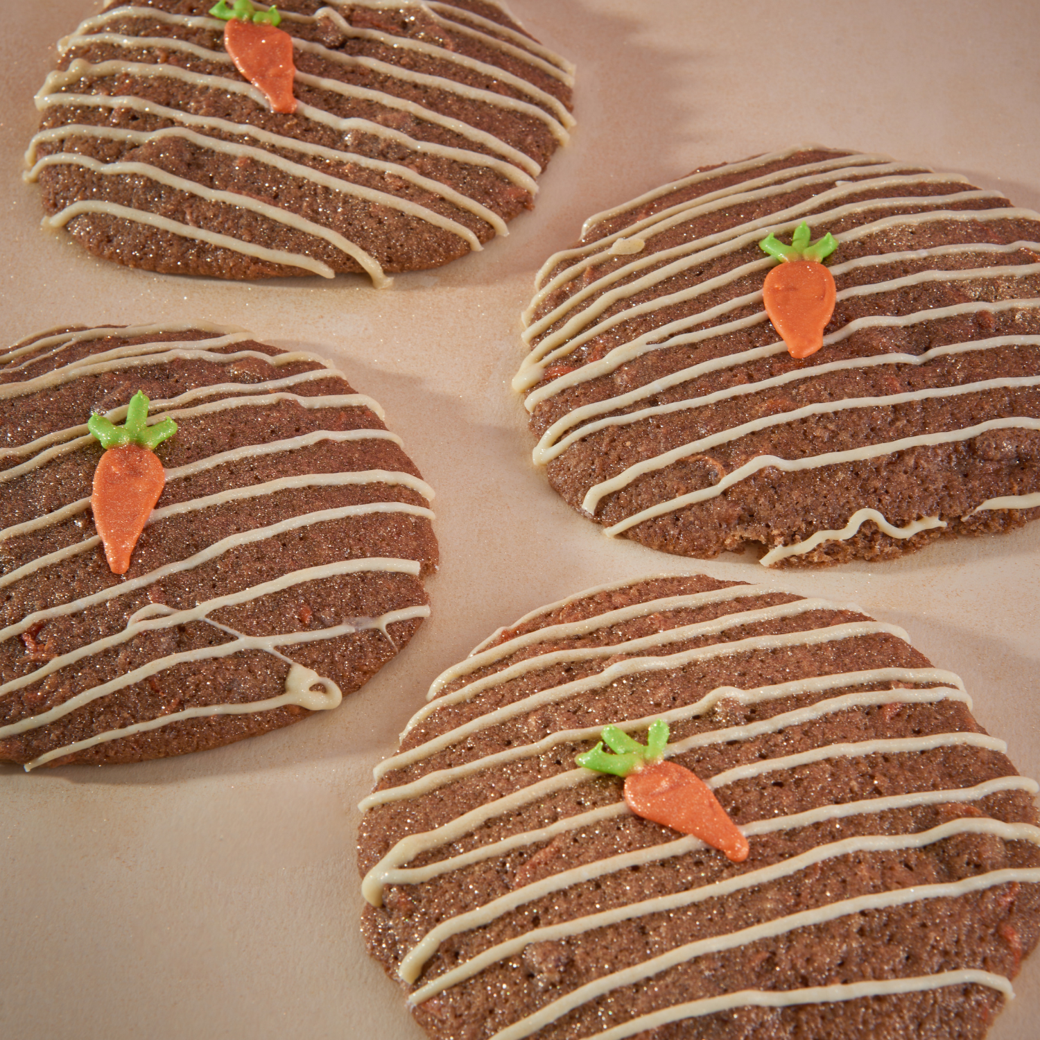 Carrot cake cookies drizzled with white icing and topped with fondant carrots