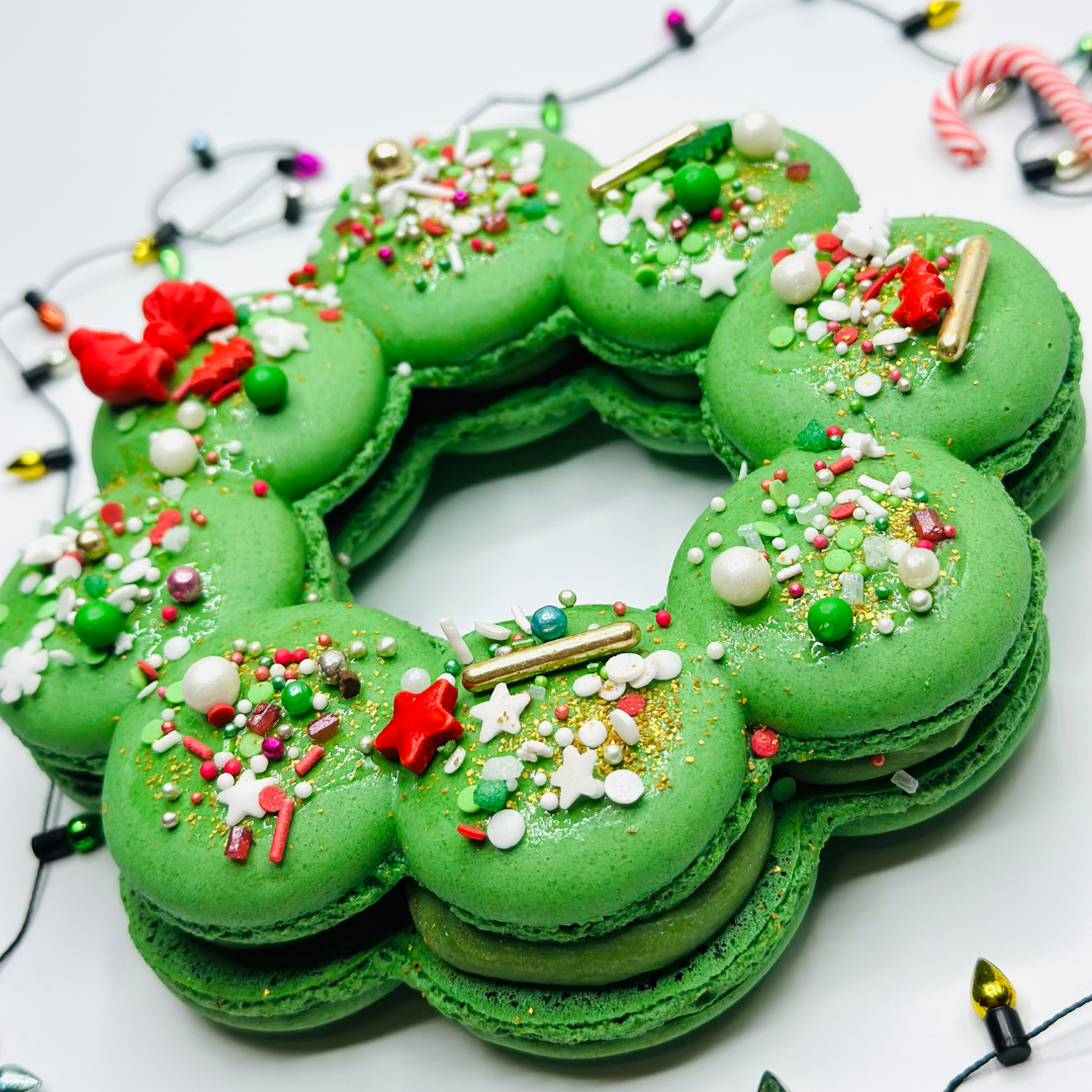Green Christmas macaron wreath decorated with sprinkles, pearls and red bows