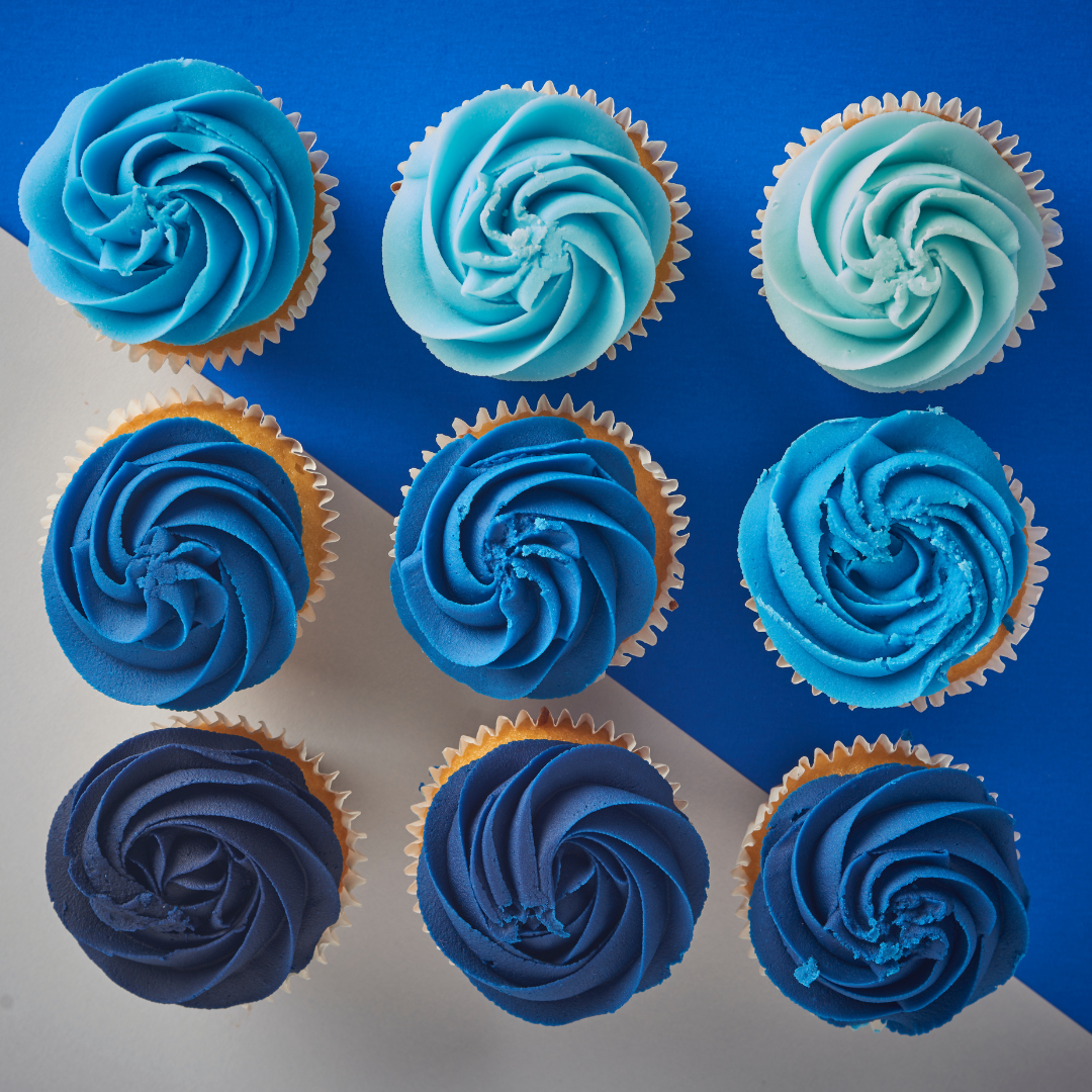 Nine blue ombre buttercream cupcakes arranged from pale blue to navy