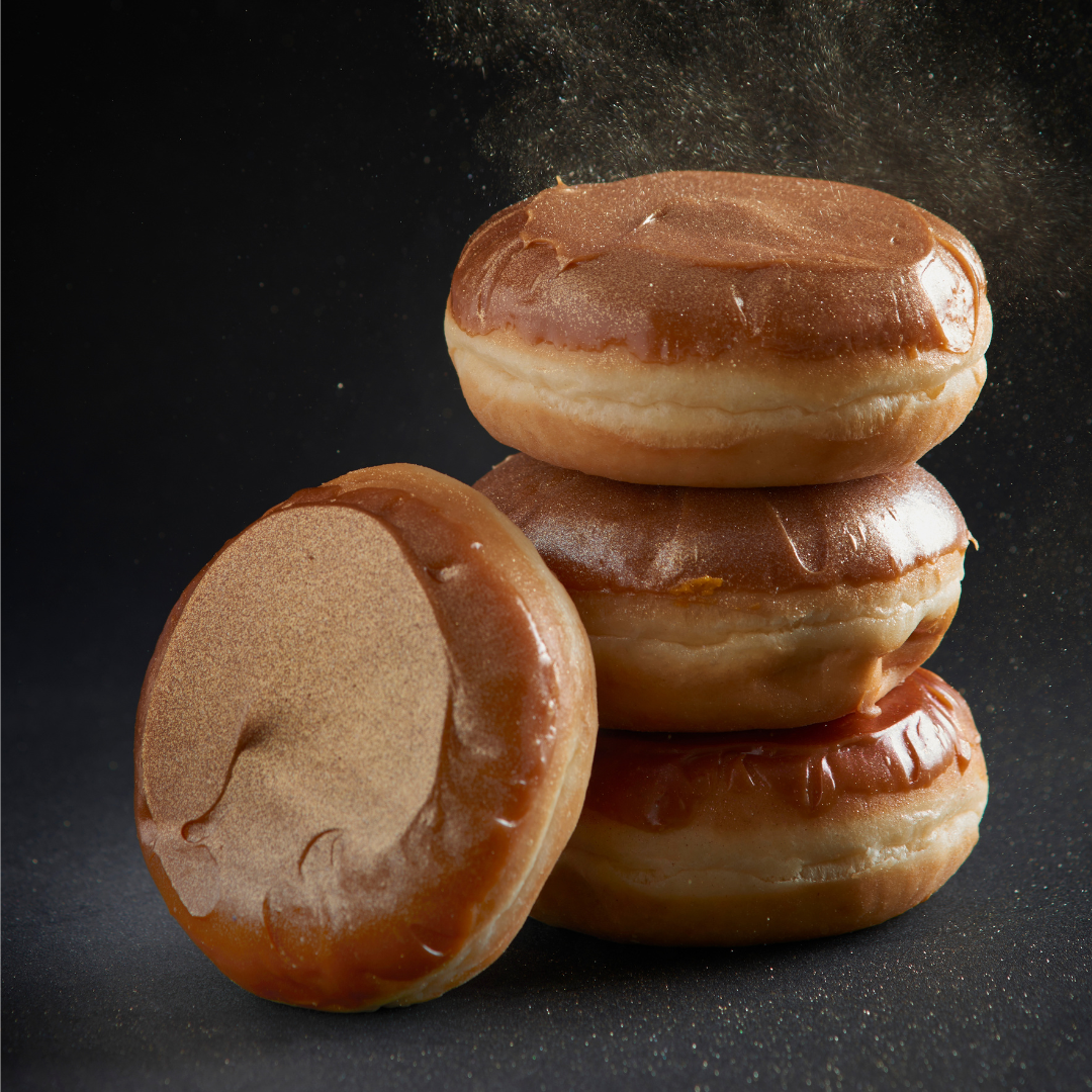 Four glazed doughnuts finished with shimmering bronze icing on a dark surface