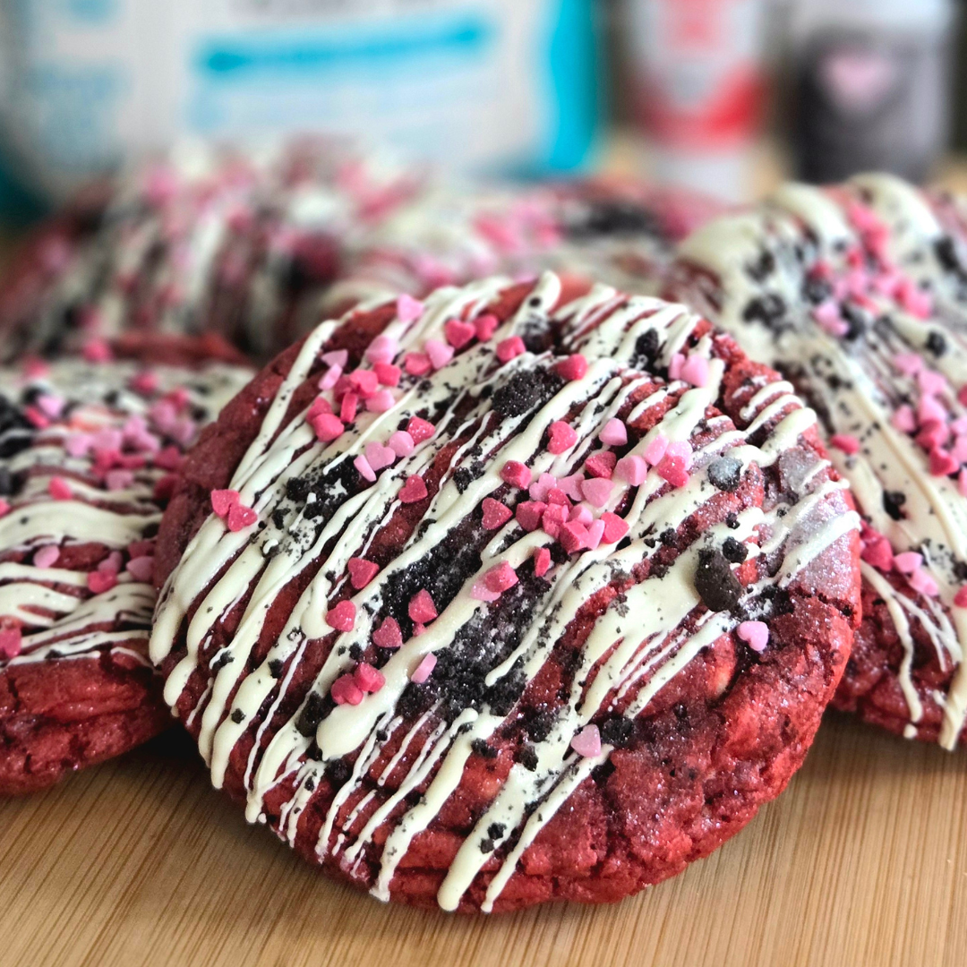 Red velvet Oreo stuffed cookies drizzled with white icing and pink sprinkles