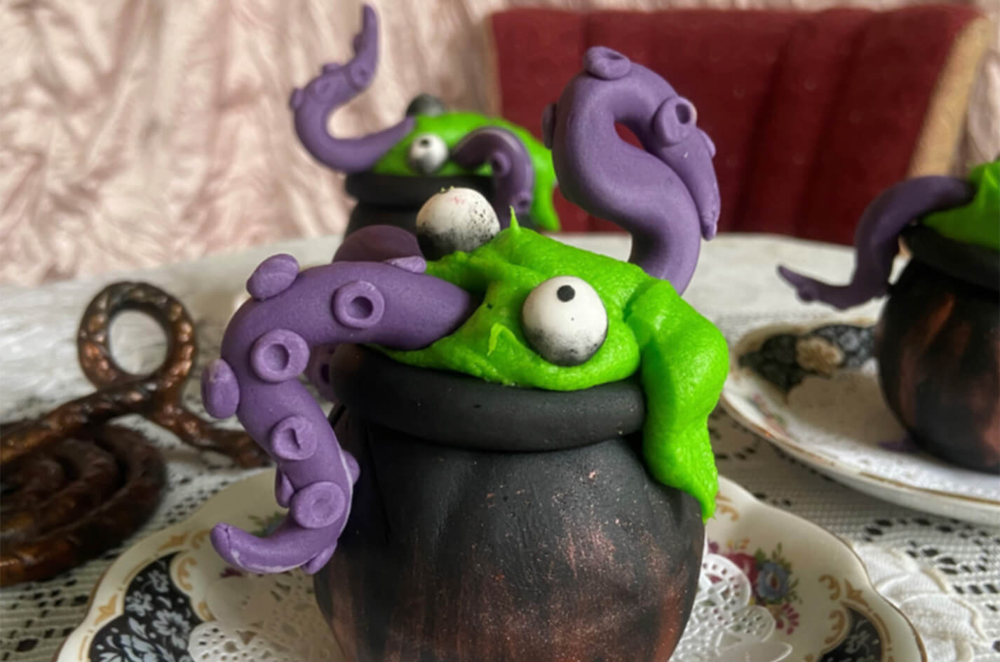 Green monster cake with purple tentacles emerging from a black cauldron