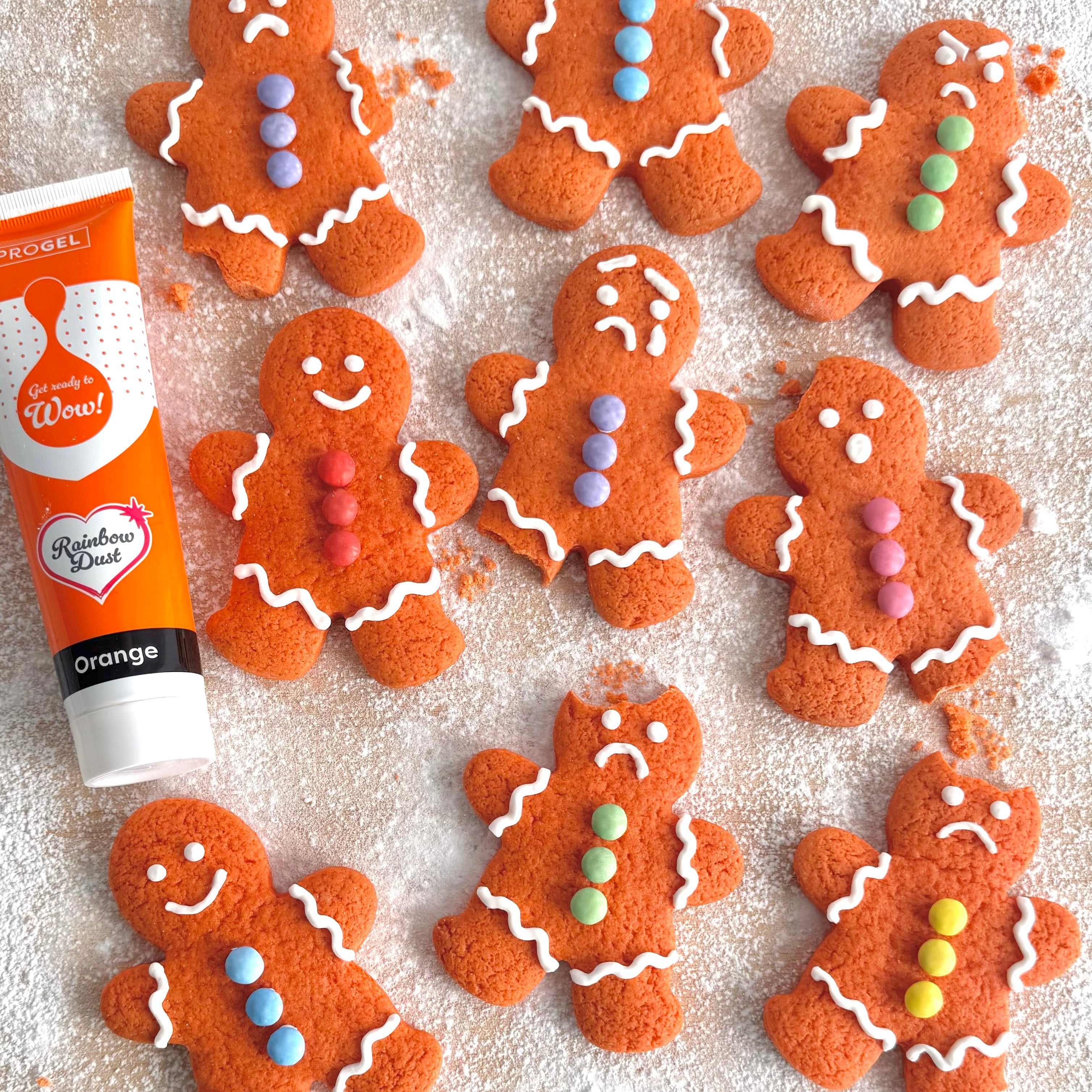 Gingerbread people decorated with white icing and colourful buttons beside orange ProGel