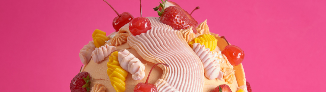 Decorative cake with fruits on a white stand against a pink background, featuring 'The Last Slice' branding.